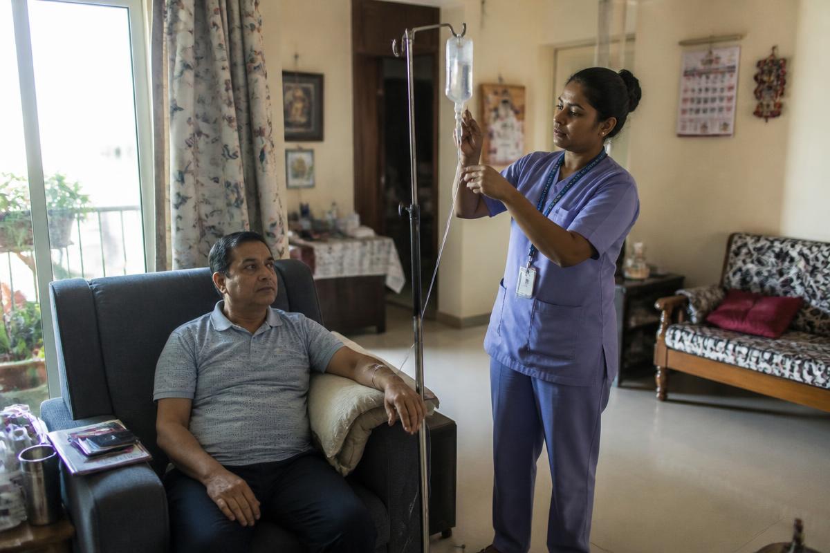 Home nurse setting up a chemotherapy infusion beside a patient in a Mumbai apartment
